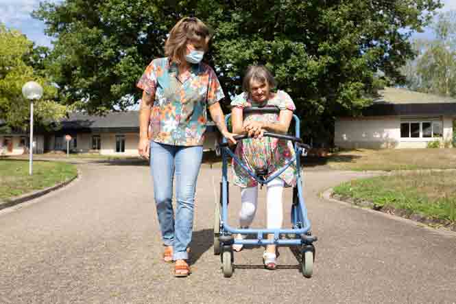 Une monitrice éducatrice se promène aux côtés d&#039;une personne en situation de handicap