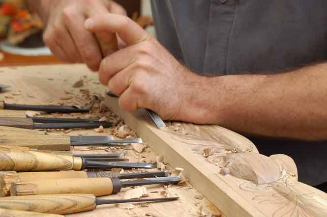 Mains sculptant des fleurs sur du bois