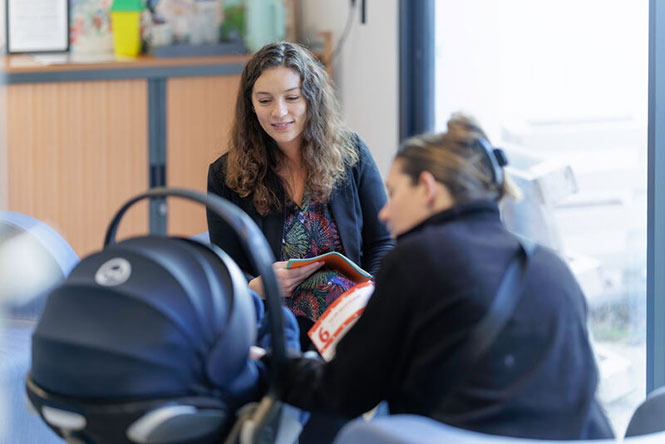 Une puéricultrice en rendez-vous avec une famille.