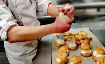 Un élève garnit des choux à la crème