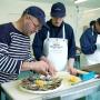 Un formateur explique la préparation d&#039;un plateau de fruits de mer à un apprenti