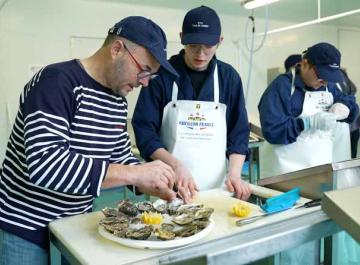 Un formateur explique la préparation d&#039;un plateau de fruits de mer à un apprenti