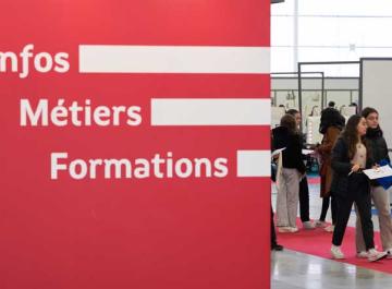 Vue d&#039;un salon d&#039;orientation avec un panneau indiquant &quot;Infos métiers formations&quot;