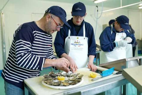 Un formateur explique la préparation d&#039;un plateau de fruits de mer à un apprenti