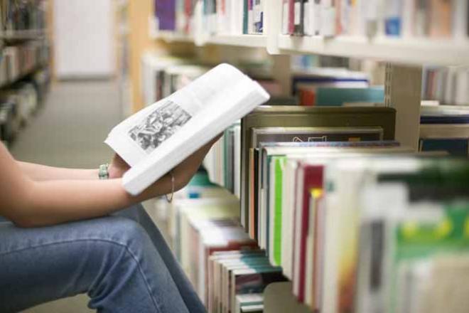 Un travail personnel important à fournir Etudiante lisant un livre dans une bibliothèque