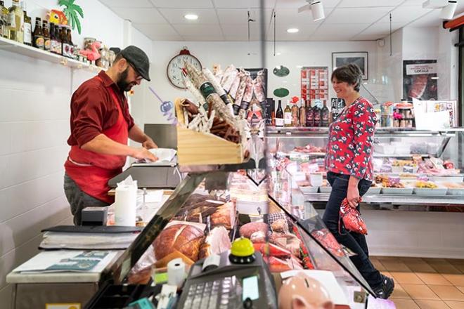 La boucherie - charcuterie - traiteur Aux délices des Gourmets à Gosne (35) Un boucher sert une cliente